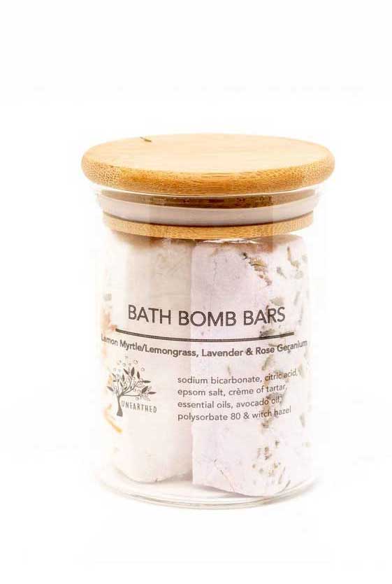 Clear gass jar and wooden lid filled with three bath bomb bars.