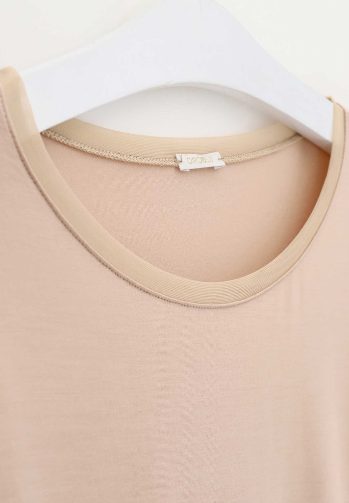 Close up of the tulle edging around the neckline of a powder coloured tee.
