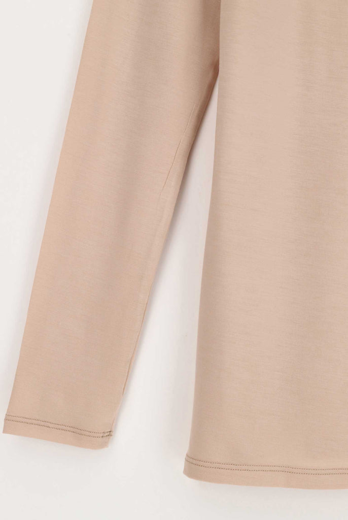 Close up of the edging of the sleeve cuff and hemline of a powder coloured long sleeved tee.