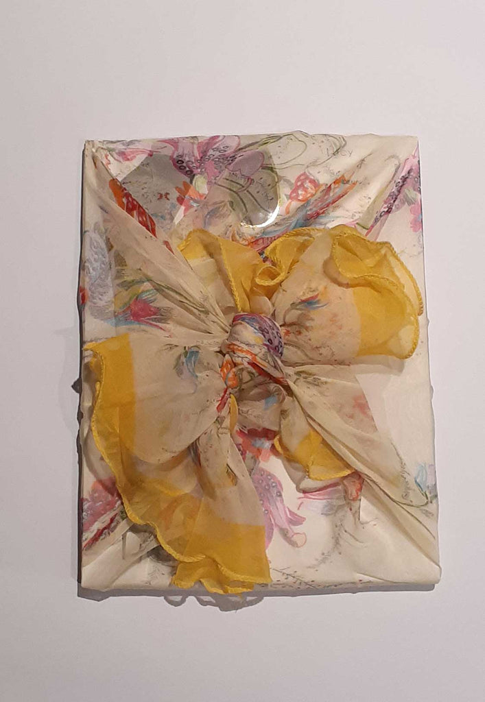 Gift wrapped in yellow floral scarf.