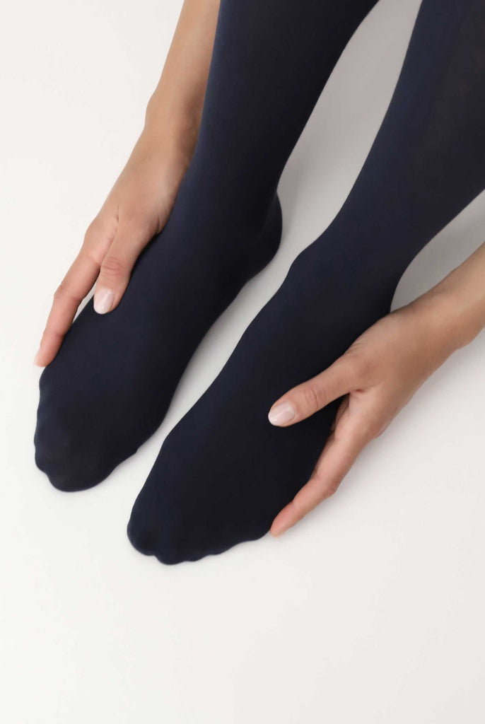 Close up of lady's feet, caressed with her hands and wearing blue tights.