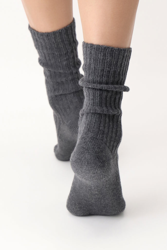 Back view of lady's feet wearing grey melange ribbed socks.