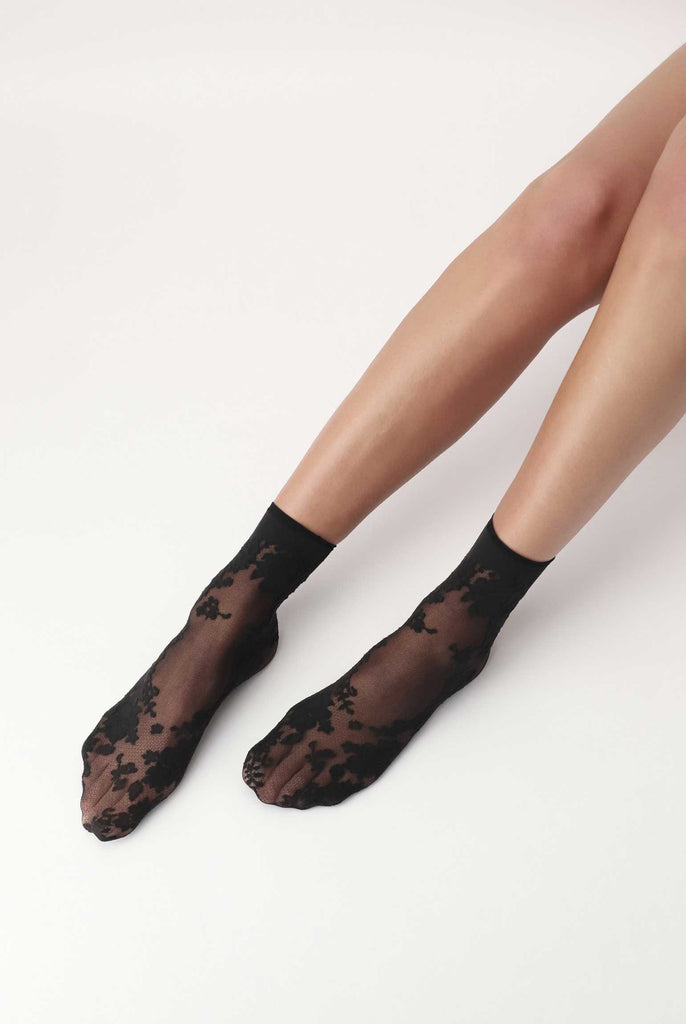 Lady's feet outstretched, wearing black lace, tulle socks.