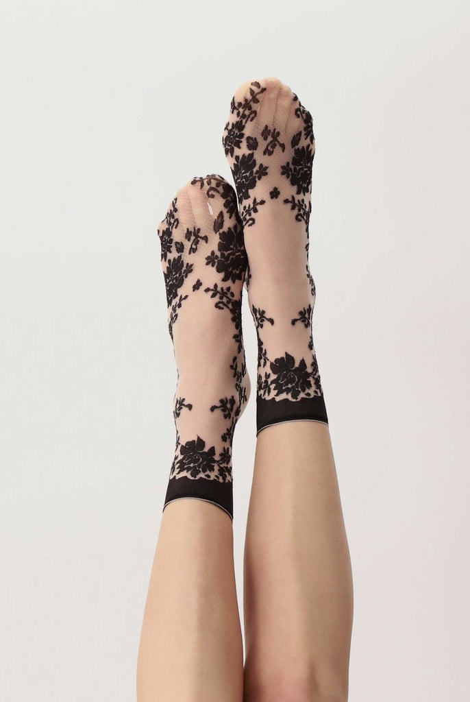 Lady's feet up in the air wearing black lace, tulle, crew socks.