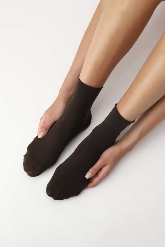 Lady's feet with hands resting on each side of her feet in black socks.