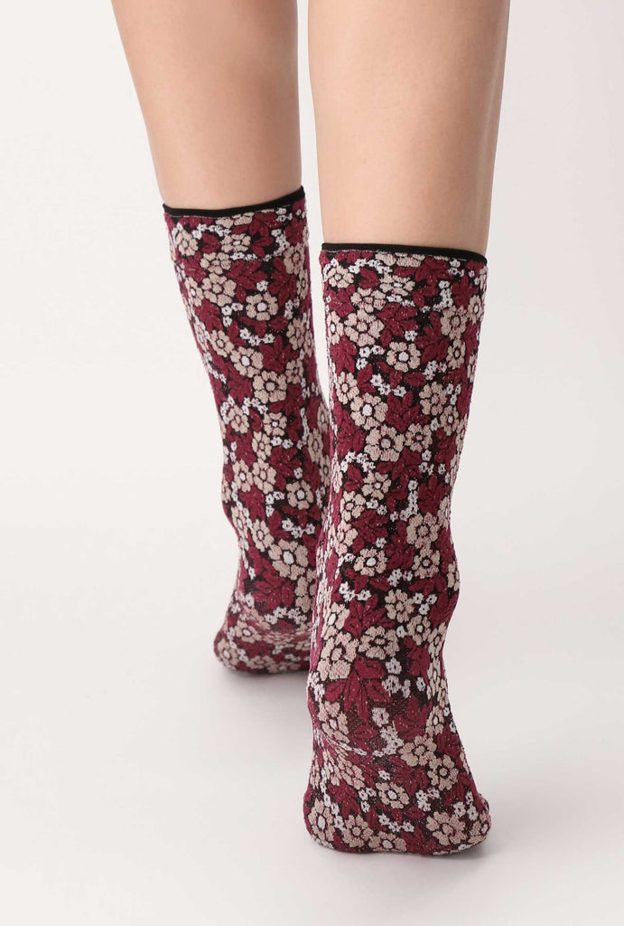 Lady's back of feet in red and white flowery print socks.