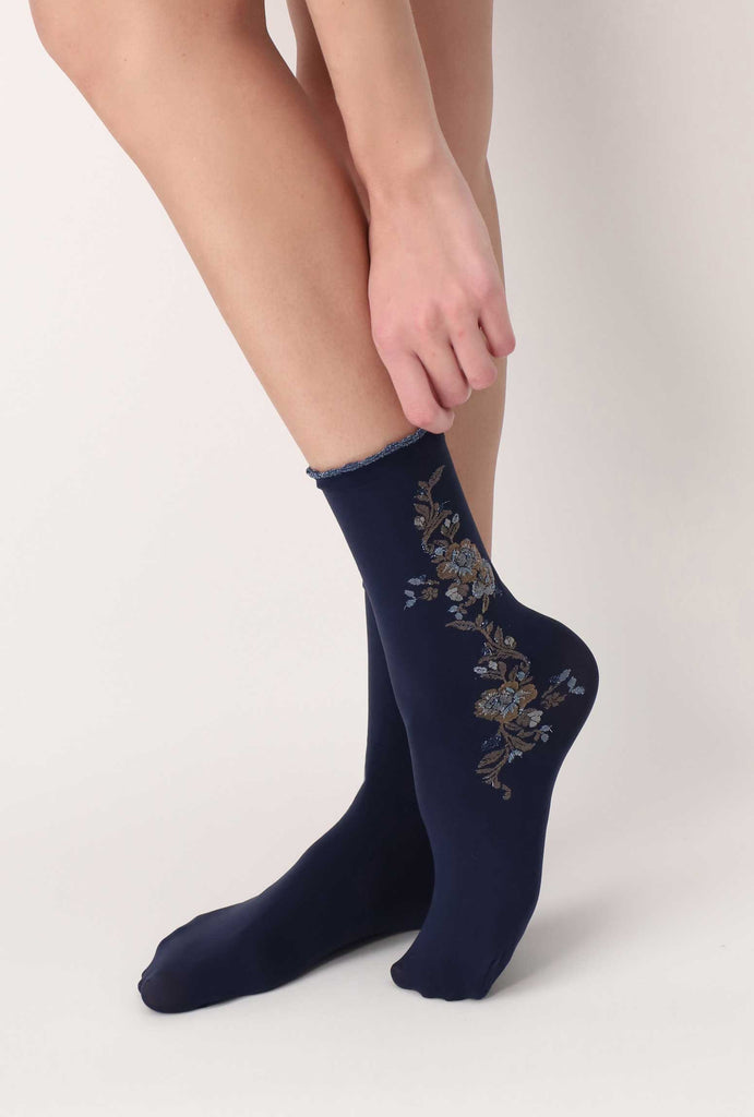 Side view of lady's foot, in blue rose patterned crew socks.