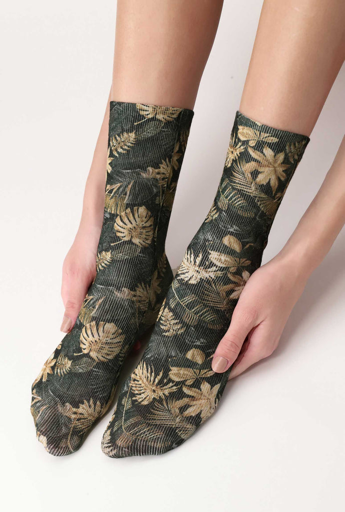 Lady's feet held by her hands, wearing jungle print green and gold socks.