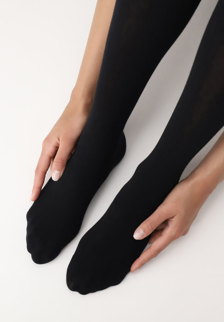 Lady's feet in black tights, held in two hands.