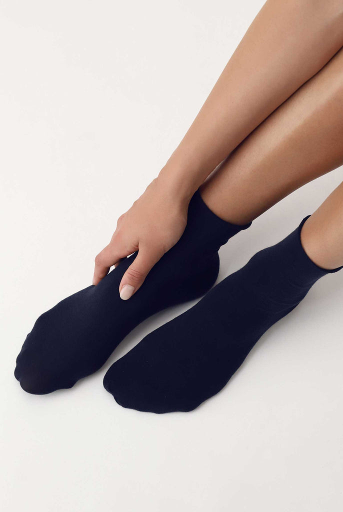 Lady's feet with hand resting on the side, wearing black socks.