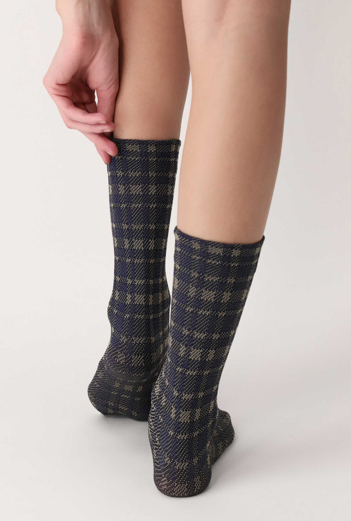 Back view of lady's feet in blue/grey tartan patterned socks.