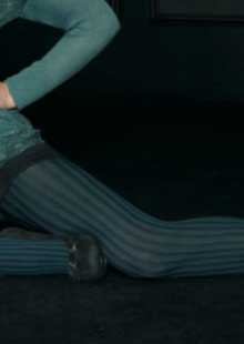 Close up of lady's thigh in forrest green tights and black shoes.
