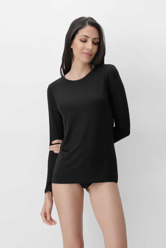 Lady. standing in pensive mode, wearing a long sleeved black tee.