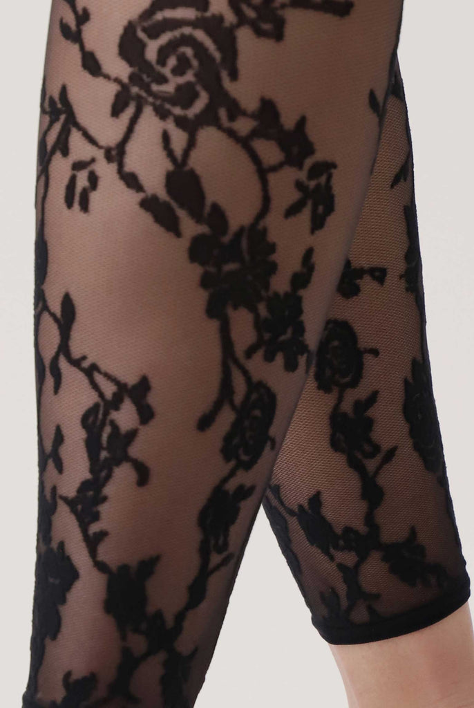 Close up of black floral pattern on a sheer footless tight on a lady's legs.
