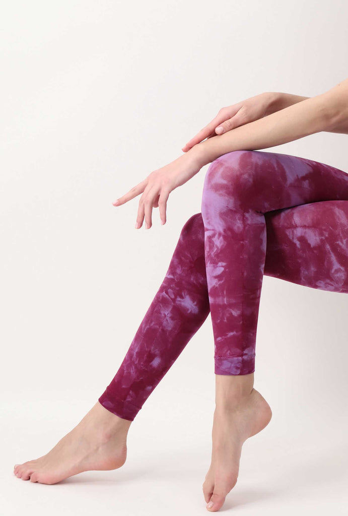 Side view of lady's lower legs. crossed over, wearing lilac pink tie-dye leggings.